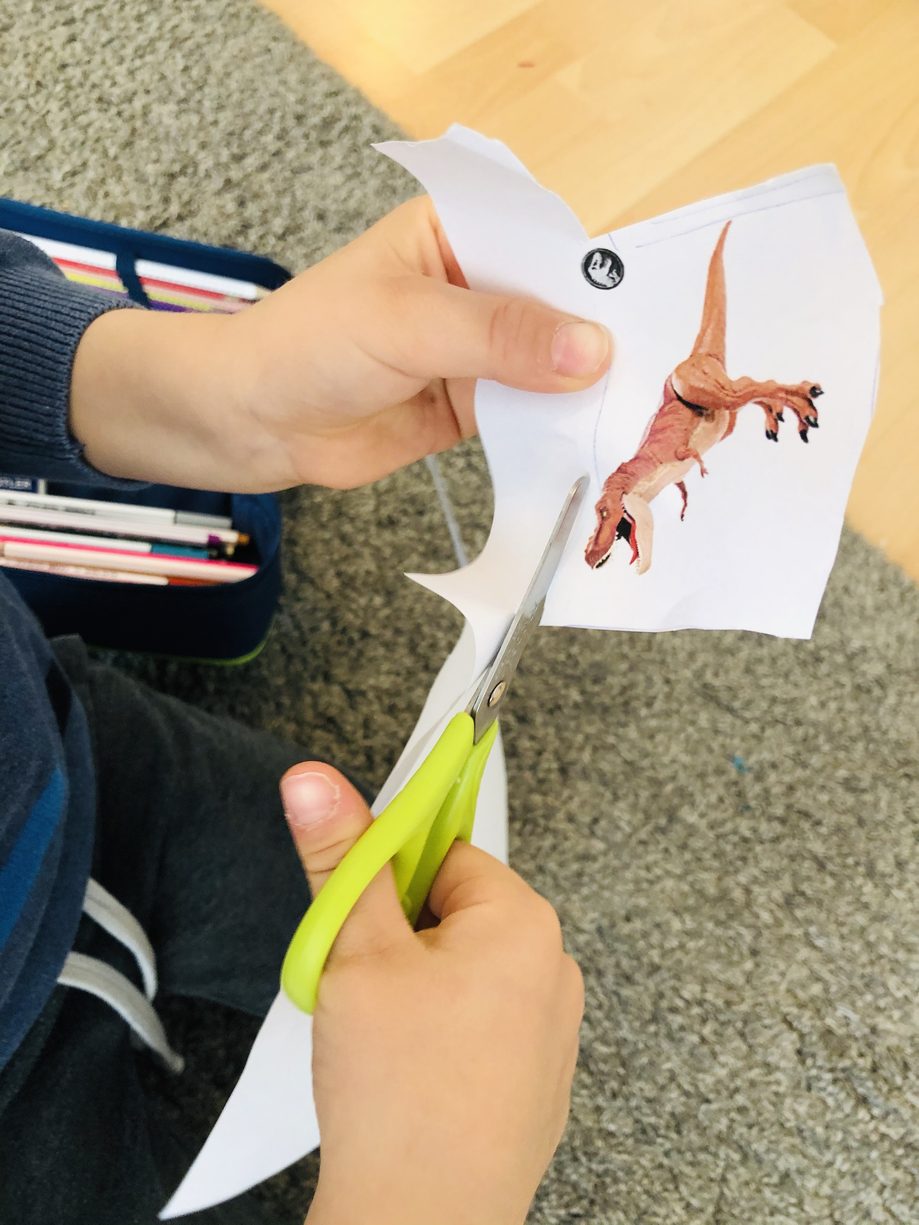 kid cutting out a dino for the numbers maze