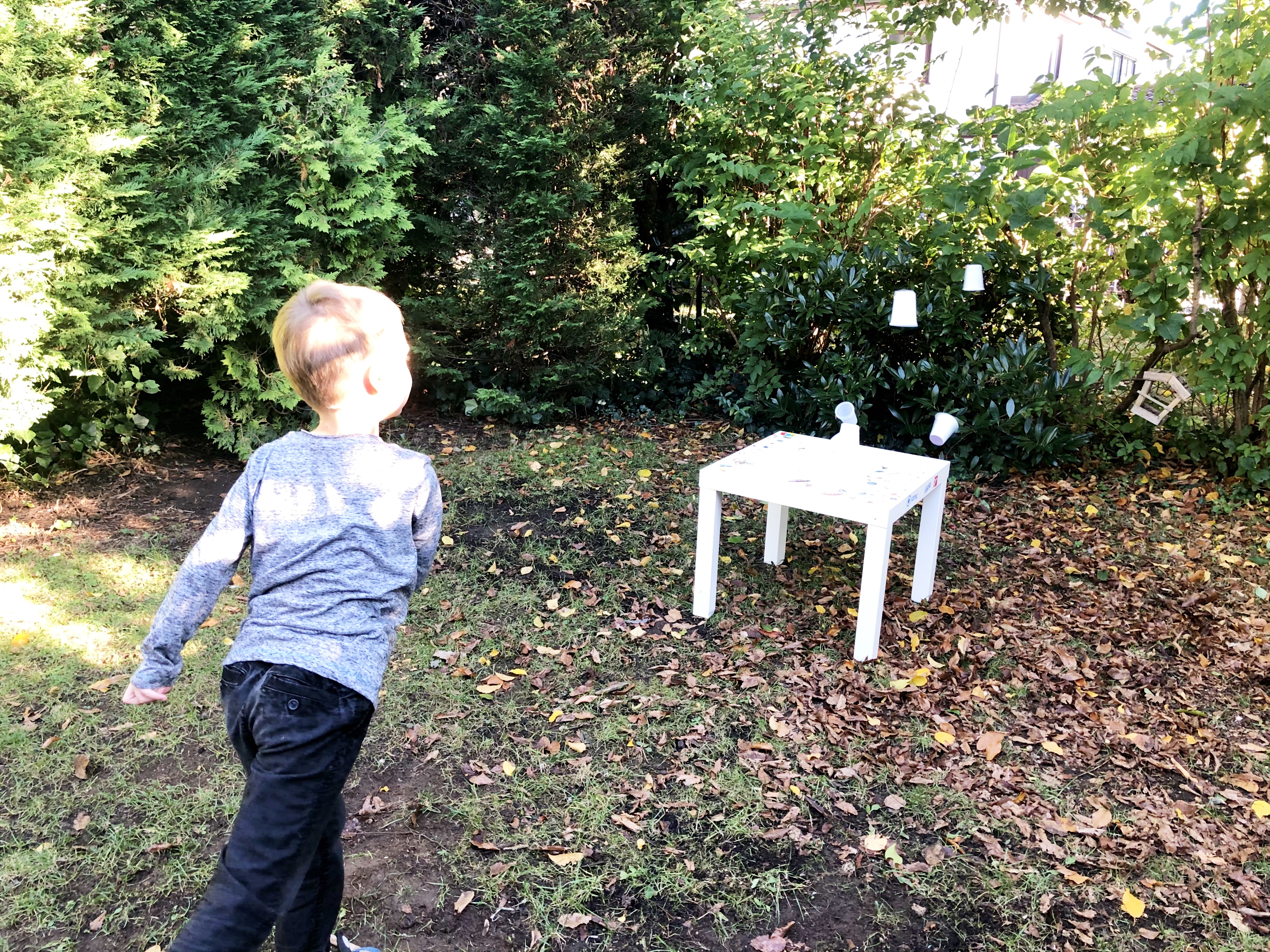 kid throwing a ball to hit the stack